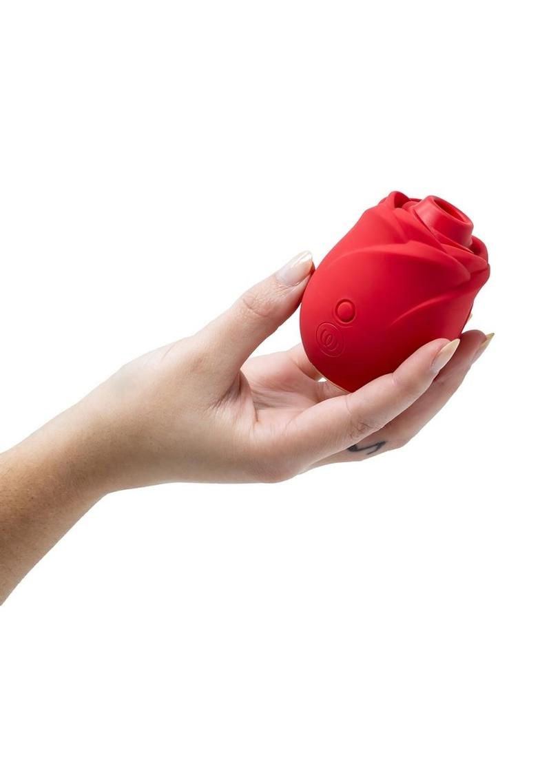 Red silicone rose held in a hand against a white background